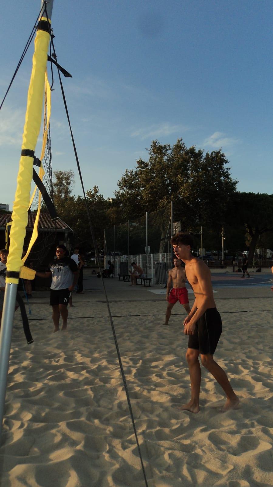 Un joueur du Mourillon Volley sur le terrain de sable, filet et pinède en fond