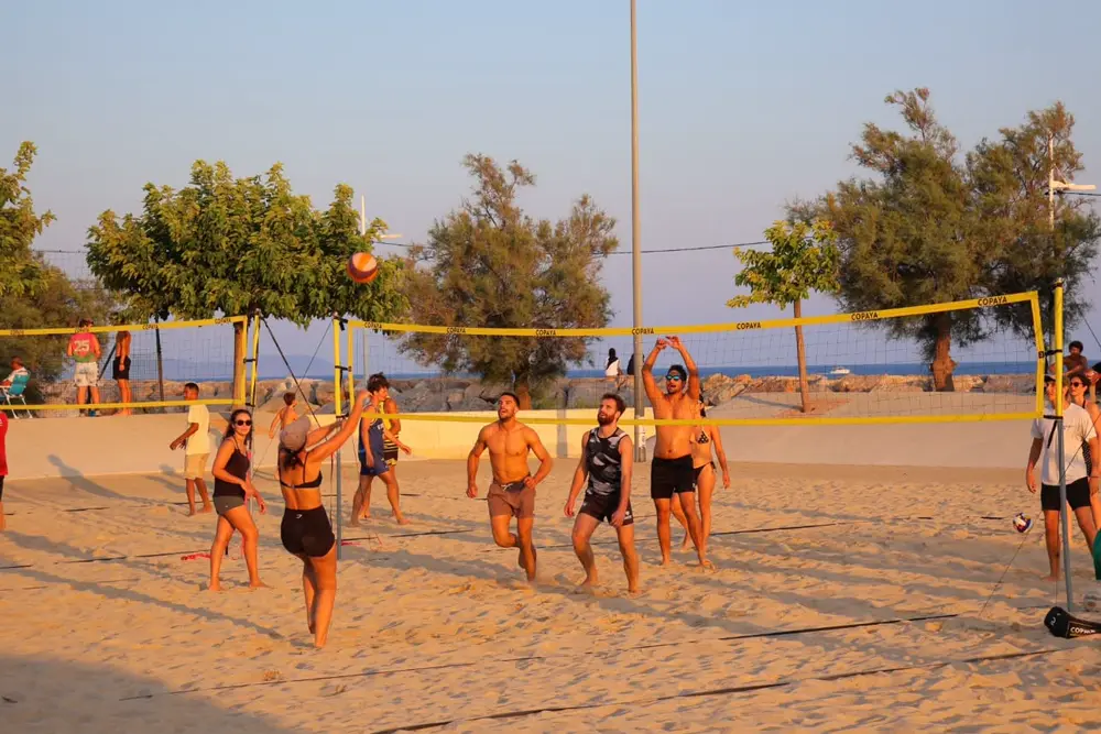 Échange en plein vol lors d'une séance de beach volley de l'asso, ballon au-dessus du filet